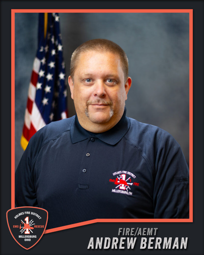 A man in a navy Holmes Fire District shirt stands in front of a U.S. flag. Text reads “Fire/AEMT Andrew Berman.” Fire department logos appear in the image corners.