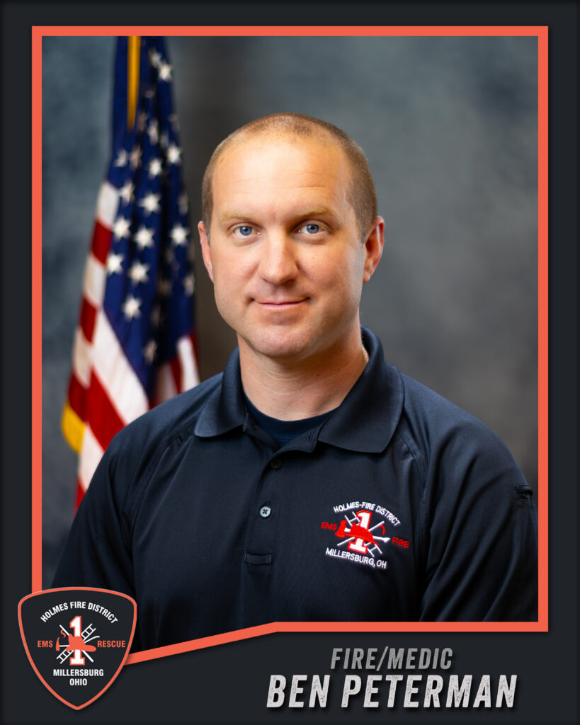 A man in a dark polo with a fire district logo poses in front of a US flag. Text reads “Holmes Fire District, Millersburg, Ohio” and “Fire/Medic Ben Peterman.”.
