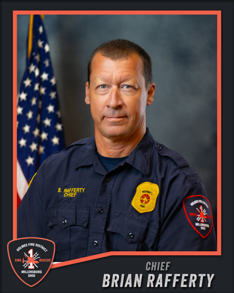 A man in a dark uniform stands in front of an American flag. His shirt has badges and a name tag that reads “B. Rafferty Chief.” Text at the bottom says “Chief Brian Rafferty, Holmes Fire District, Millersburg, Ohio.”.