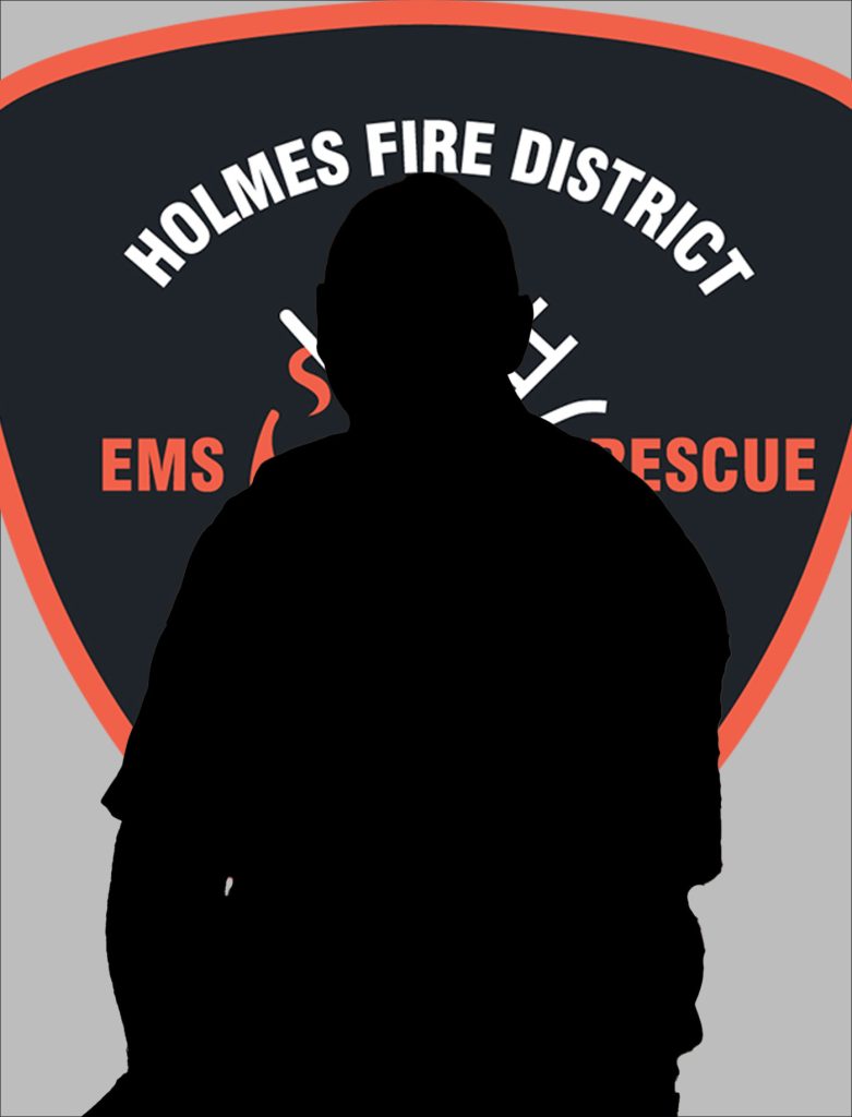 A silhouette of a person is in front of a large logo that reads "Holmes Fire District EMS Rescue" with an emblem of a flame and medical symbols in the center. The logo is in the shape of a shield and is primarily black with orange and white details.