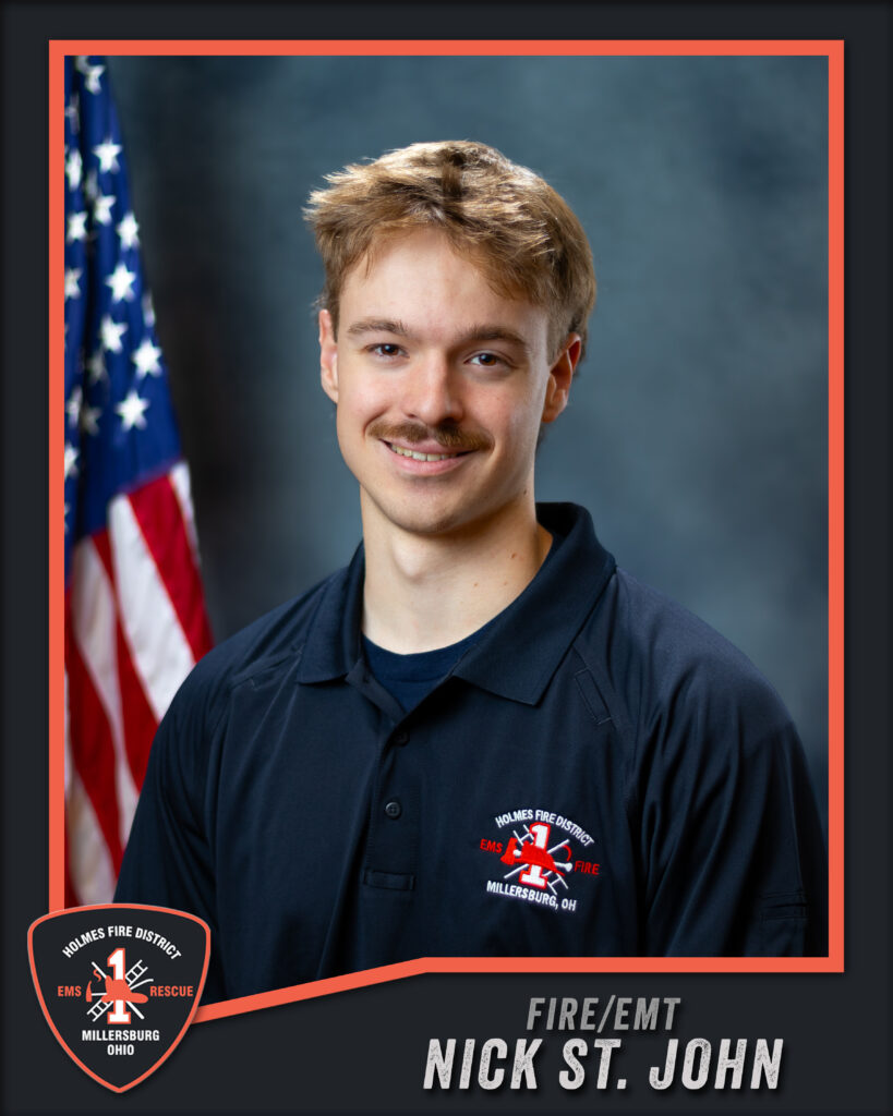 A young man in a dark uniform with a fire district logo stands in front of a US flag. Text reads “FIRE/EMT Nick St. John, Holmes Fire District, Millersburg, Ohio.”.